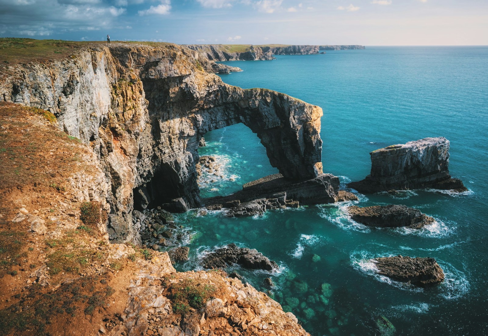 Green Bridge of Wales Castlemartin Wales gray and brown rock formation and mountain near body of water